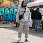 Modello alla moda in Trapstar Tuta contro uno sfondo urbano che mostra le tendenze della moda streetwear.